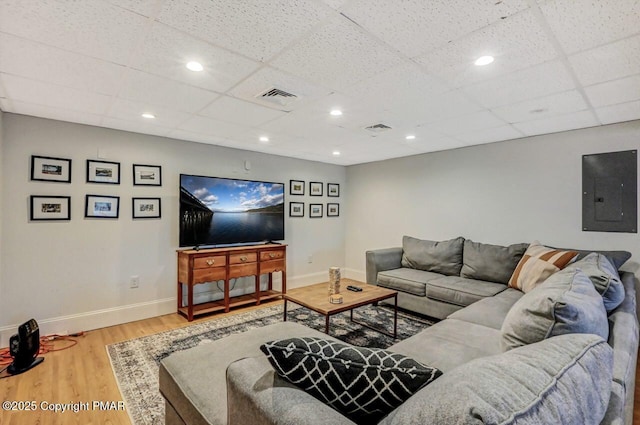 living room featuring baseboards, electric panel, visible vents, and wood finished floors