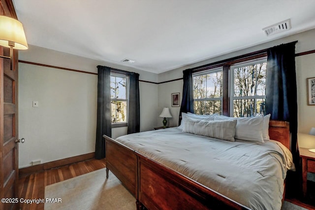 bedroom with visible vents, baseboards, and wood finished floors