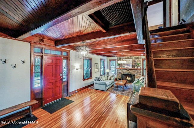 foyer entrance featuring hardwood / wood-style flooring, a fireplace, a chandelier, and beamed ceiling