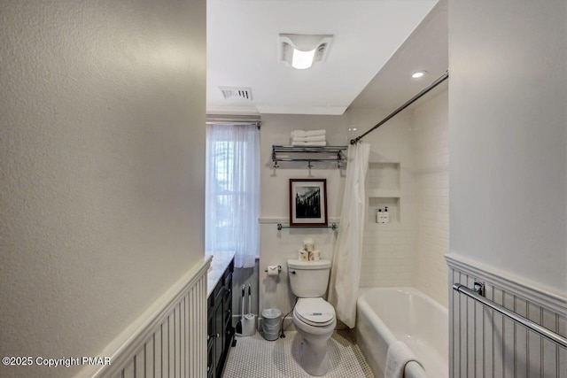 bathroom with visible vents, a decorative wall, shower / bathtub combination with curtain, toilet, and wainscoting