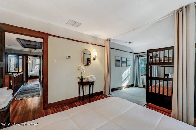 corridor with baseboards, visible vents, vaulted ceiling, and wood finished floors