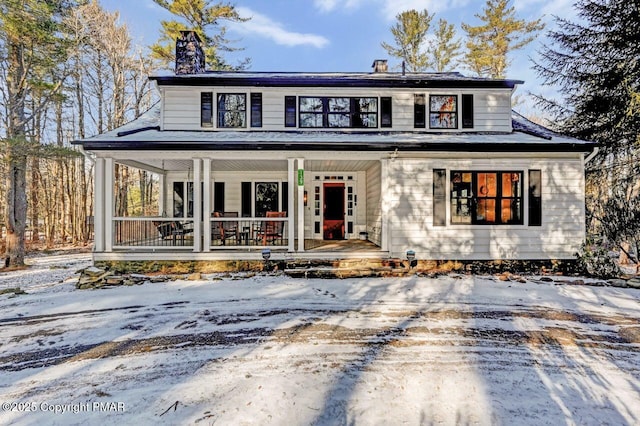 view of front facade featuring a chimney and a porch