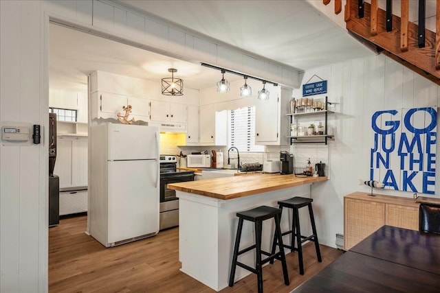 62 Locust Ln, Gouldsboro, PA 18424 - kitchen with wood finished floors, a peninsula, under cabinet range hood, white appliances, and wood counters