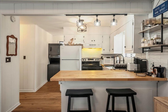 62 Locust Ln, Gouldsboro, PA 18424 - kitchen with butcher block countertops, a peninsula, stacked washer / dryer, under cabinet range hood, and white appliances