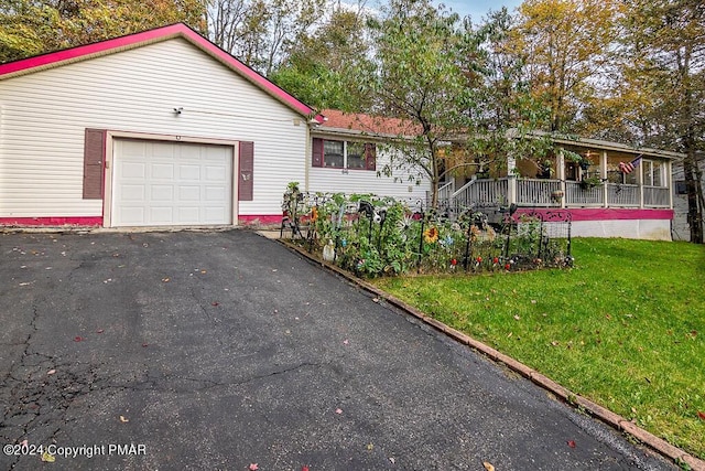 single story home with a front yard, covered porch, a garage, and aphalt driveway