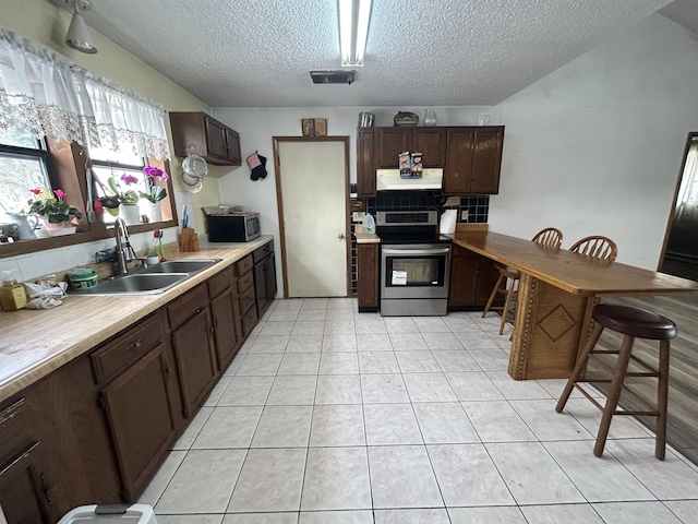 kitchen with a sink, dark brown cabinets, under cabinet range hood, appliances with stainless steel finishes, and backsplash