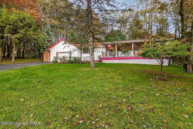 view of front of property featuring a front lawn, a porch, an attached garage, and aphalt driveway