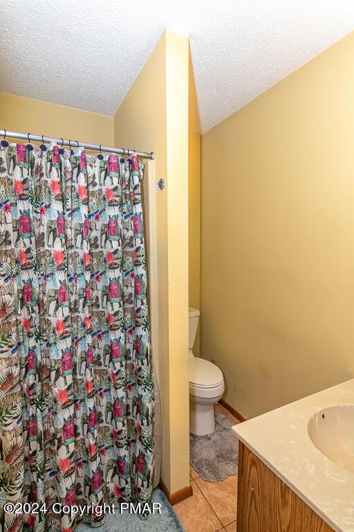 full bathroom with a shower with curtain, toilet, tile patterned flooring, and a textured ceiling