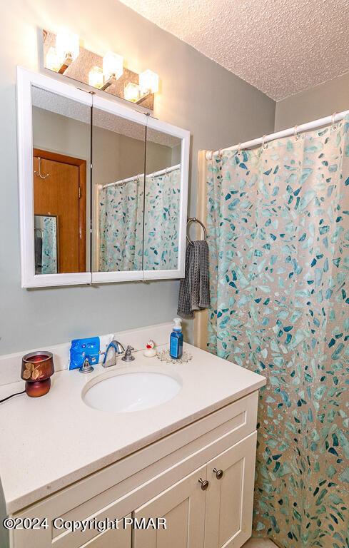 full bath with vanity and a textured ceiling