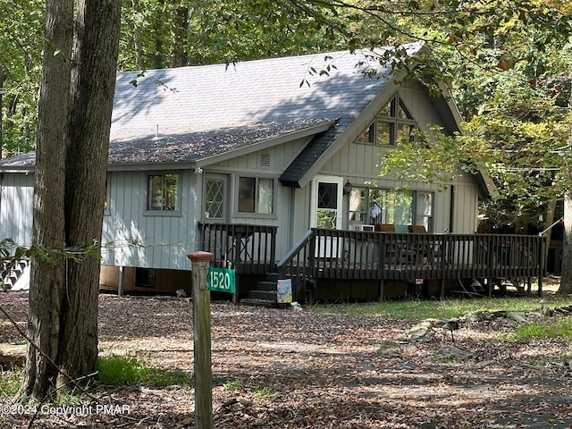 view of front facade featuring roof with shingles and a wooden deck