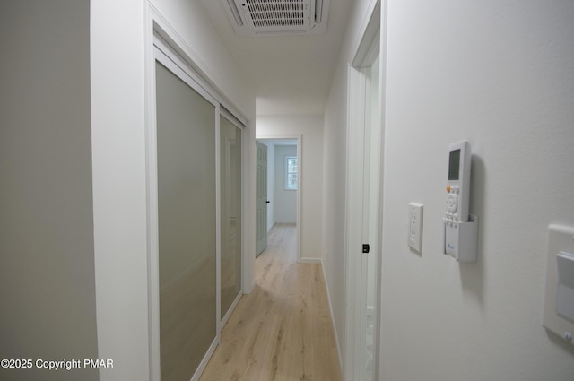 corridor featuring light wood finished floors, visible vents, and baseboards