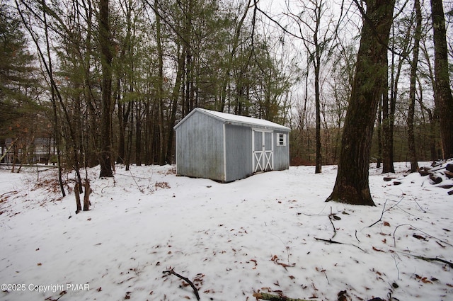 snow covered structure with a shed