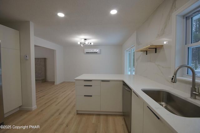 kitchen with light countertops, a wall unit AC, a peninsula, and a sink