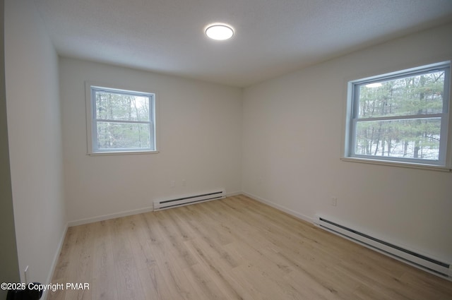 unfurnished room featuring light wood-type flooring, baseboards, and a baseboard heating unit