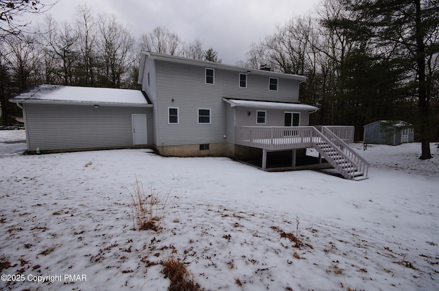 snow covered back of property featuring a deck