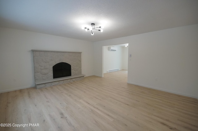 unfurnished living room featuring a fireplace, baseboards, light wood-style floors, baseboard heating, and a wall mounted air conditioner