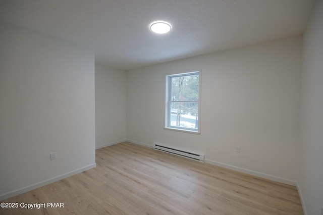 empty room with baseboards, a baseboard radiator, and light wood-style floors