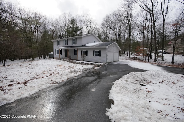 view of front of home featuring driveway, a chimney, and an attached garage