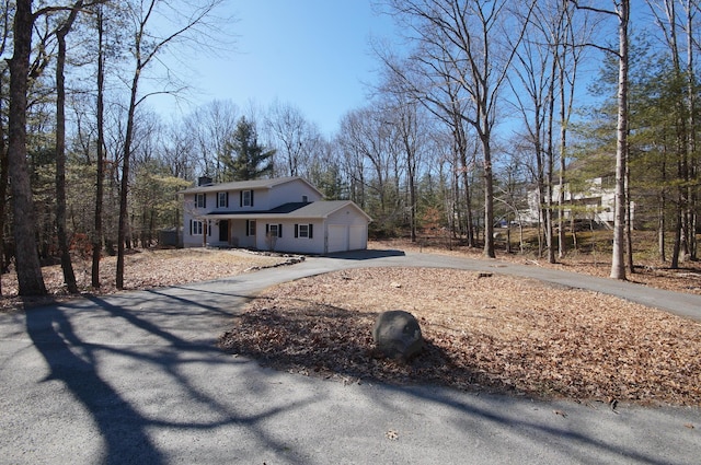 view of front of property featuring a garage, aphalt driveway, and a chimney