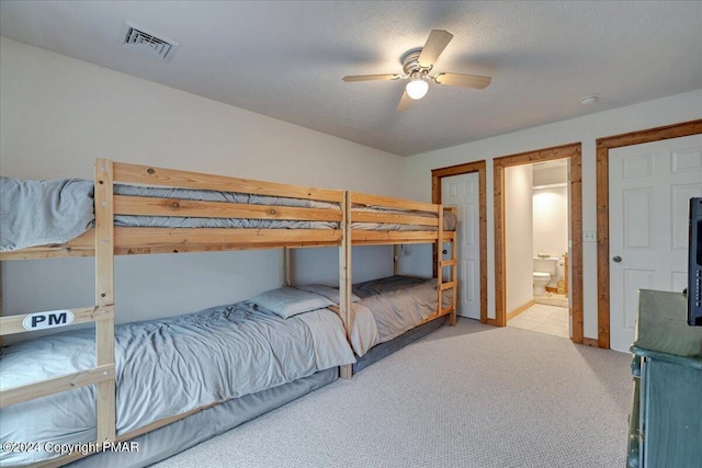 bedroom featuring ceiling fan, a textured ceiling, connected bathroom, carpet floors, and visible vents