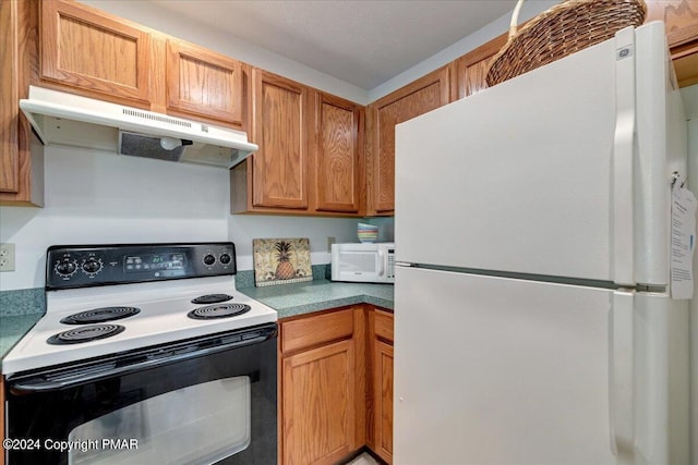 kitchen featuring white appliances, brown cabinets, and under cabinet range hood