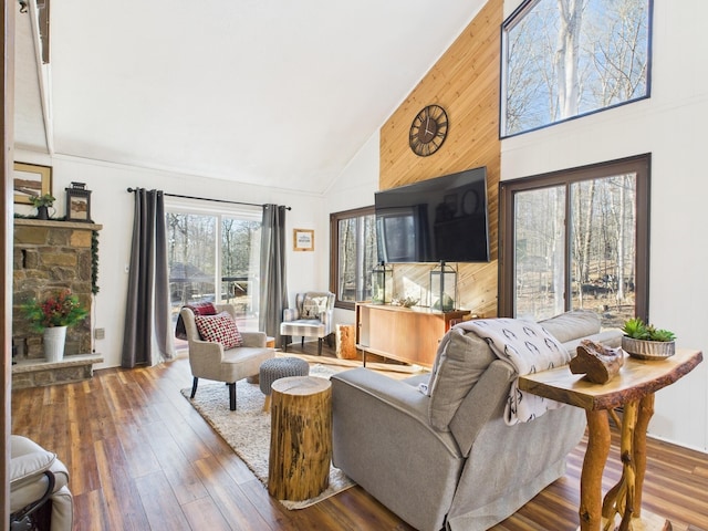 living room featuring high vaulted ceiling, wood walls, and wood finished floors