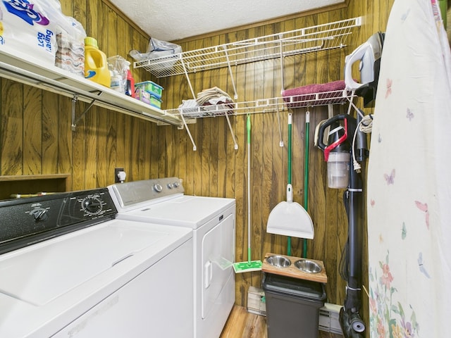 washroom featuring light wood-style floors, washing machine and dryer, wood walls, a textured ceiling, and laundry area