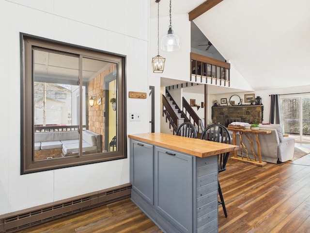 kitchen featuring vaulted ceiling with beams, a baseboard heating unit, butcher block countertops, a fireplace, and dark wood finished floors