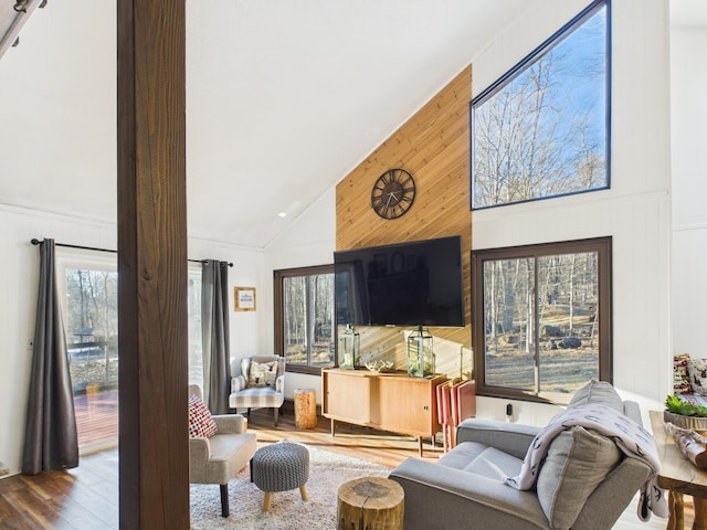 living room featuring high vaulted ceiling, wood walls, and wood finished floors