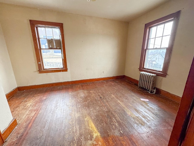 empty room with radiator, hardwood / wood-style flooring, and plenty of natural light