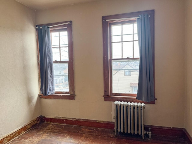 unfurnished room with radiator heating unit and baseboards