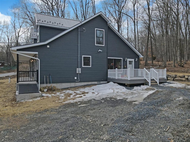 back of property with metal roof and a wooden deck