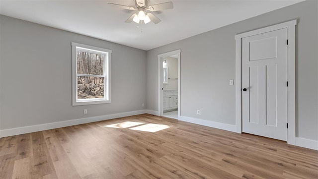 unfurnished bedroom featuring a ceiling fan, light wood-type flooring, baseboards, and ensuite bathroom