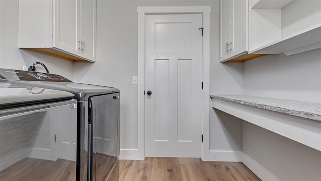 laundry area featuring washer and dryer, baseboards, cabinet space, and light wood finished floors