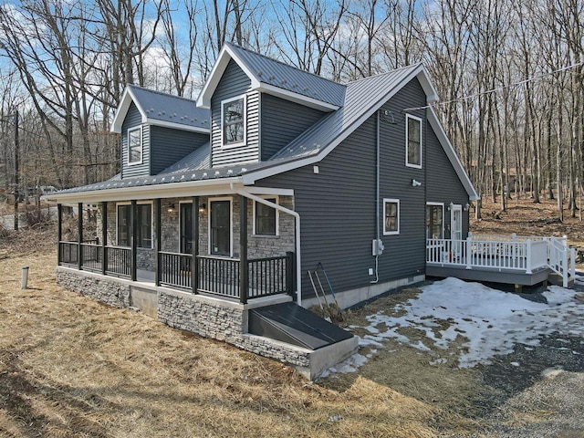 exterior space featuring a porch, stone siding, metal roof, and a wooden deck