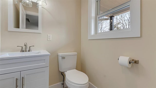 half bathroom featuring baseboards, vanity, and toilet