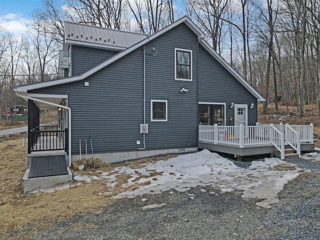 back of house with metal roof and a deck