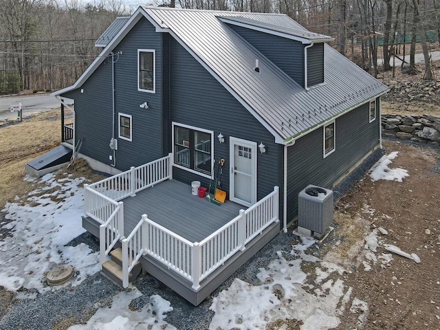 rear view of property featuring metal roof, central AC unit, and a wooden deck