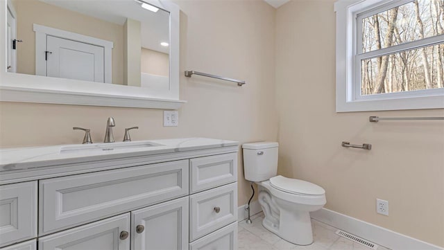 bathroom with toilet, visible vents, vanity, baseboards, and marble finish floor