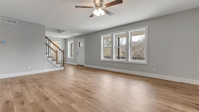 unfurnished living room featuring light wood-style floors, visible vents, stairway, and baseboards