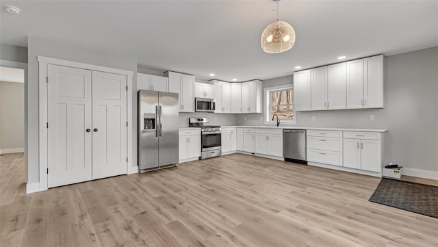 kitchen with light wood-style flooring, appliances with stainless steel finishes, light countertops, and a sink