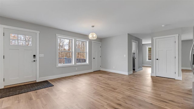 foyer with light wood-type flooring, plenty of natural light, and baseboards