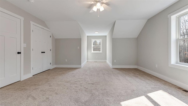 additional living space with lofted ceiling, light carpet, visible vents, and baseboards