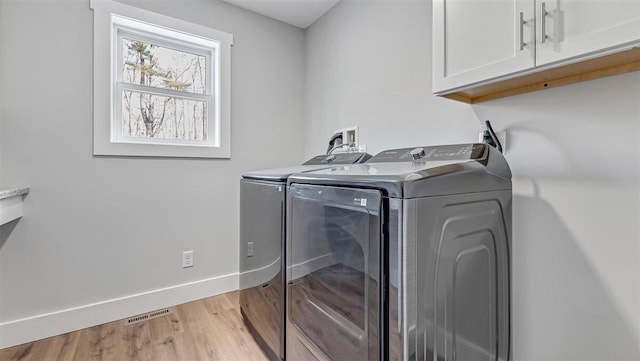 washroom with washing machine and clothes dryer, cabinet space, visible vents, light wood-style floors, and baseboards