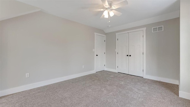 unfurnished bedroom with lofted ceiling, carpet flooring, visible vents, baseboards, and a closet