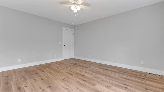 empty room featuring a ceiling fan, light wood-type flooring, visible vents, and baseboards