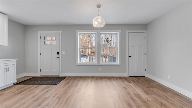 foyer with light wood-style flooring and baseboards