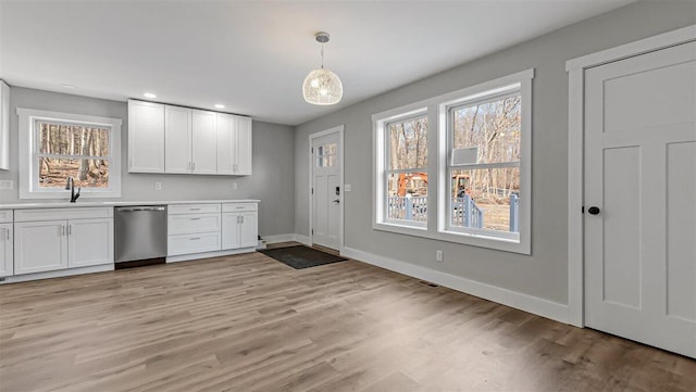 kitchen with baseboards, white cabinets, a sink, and stainless steel dishwasher