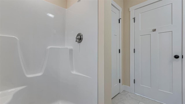 bathroom featuring marble finish floor and walk in shower