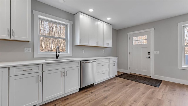 kitchen featuring a sink, white cabinetry, light countertops, and stainless steel dishwasher